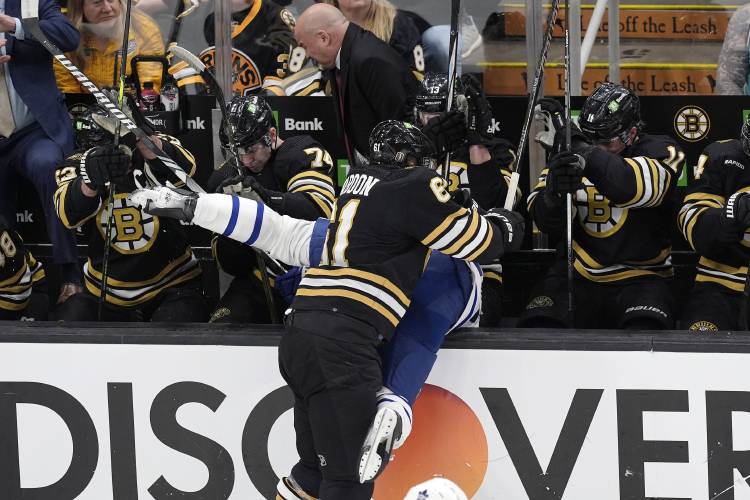 Boston Bruins' Pat Maroon (61) checks Toronto Maple Leafs' Timothy Liljegren into the Bruins' bench during the first period in Game 1 of an NHL hockey Stanley Cup first-round playoff series Saturday, April 20, 2024, in Boston. (AP Photo/Michael Dwyer)