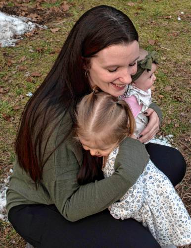  Kellyann Kaiser hugs her daughter Bailee while holding Avaree as she and Ian Goudreau play with their children outside Kaiser’s home in Ware. 