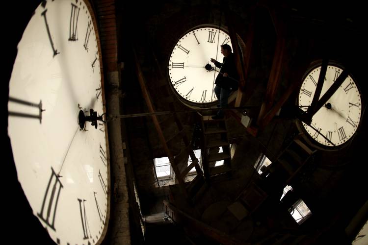 FILE - Custodian Ray Keen inspects a clock face before changing the time on the 100-year-old clock atop the Clay County Courthouse Saturday, March 8, 2014, in Clay Center, Kan. For the first time in history, world timekeepers may have to consider subtracting a second from our clocks in a few years because the planet is rotating a tad faster. (AP Photo/Charlie Riedel, File)