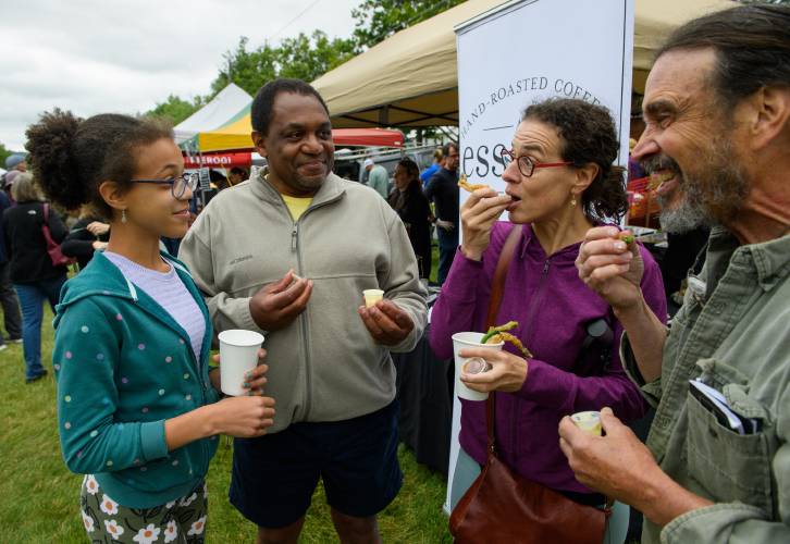 Amherst residents Lena Grant-Giraud, from left, Andrew Grant-Thomas, Melissa Giraud and Tim Holcomb feast on Esselon Cafe’s fried asparagus during thes Asparagus Festival on the Town Common on June 3, 2023.