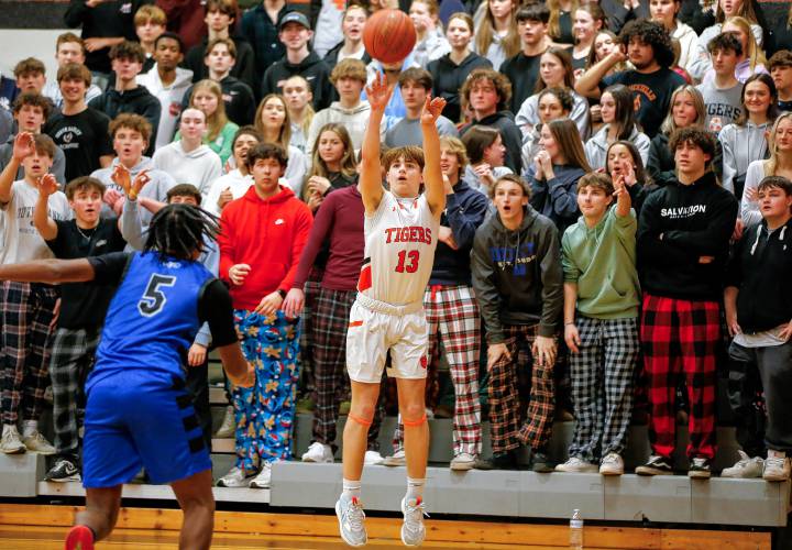 The South Hadley student section looks on as Noah Hambley (13) puts up a three-point shot in the fourth quarter against Granby on Wednesday night in South Hadley.