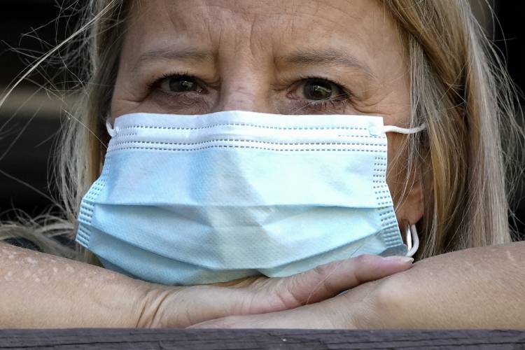  A woman wears a mask at her home after previously having COVID. The Centers for Disease Control is considering loosening isolation rules for people who get the disease. 