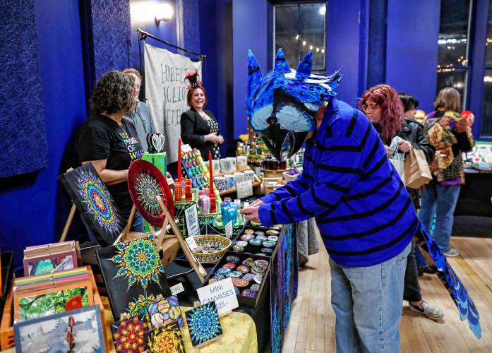 Brian McQuillan, dressed as a blue jay, peruses creations from Celeste Rocks at the City Space pop-up market, where costumes were encouraged Thursday night during Easthampton City Arts’ monthly Art Walk event.