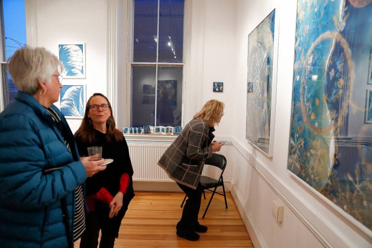 Susanne Personette, left, talks with artist Madge Evers as Maggie Hodges takes a closer look at Evers’ multimedia cyanotype imagery Thursday night at City Space during the Easthampton City Arts monthly Art Walk event.