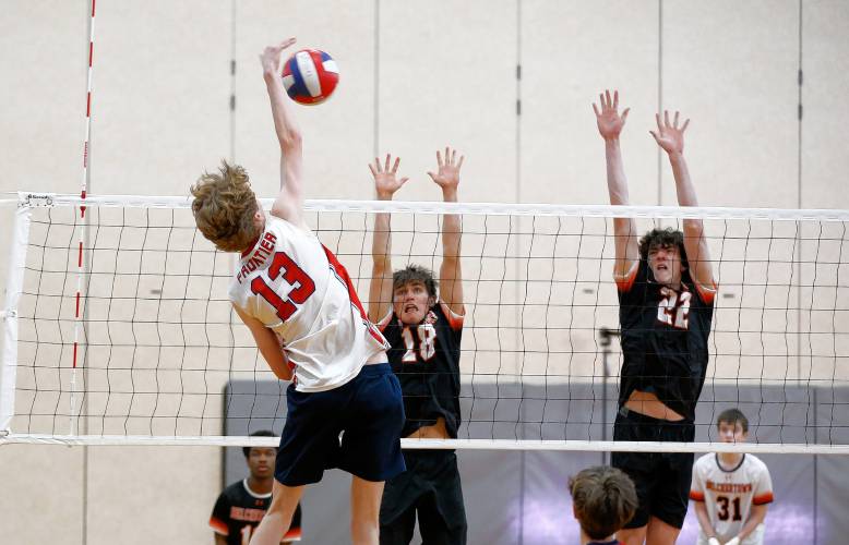 Frontier’s Jack Carey (13) attacks at the net as Belchertown’s Rainer Kristensen (18) and Shea MacLean (22) move to block in the second set Tuesday in Belchertown.